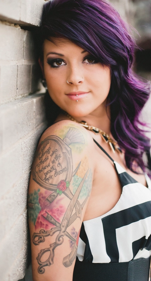 Tattooed punk rock girl with long dark purple ombre hairstyle with one undercut side